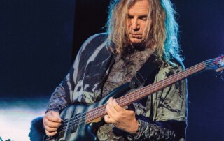 Billy Sherwood plays a bass guitar on stage.